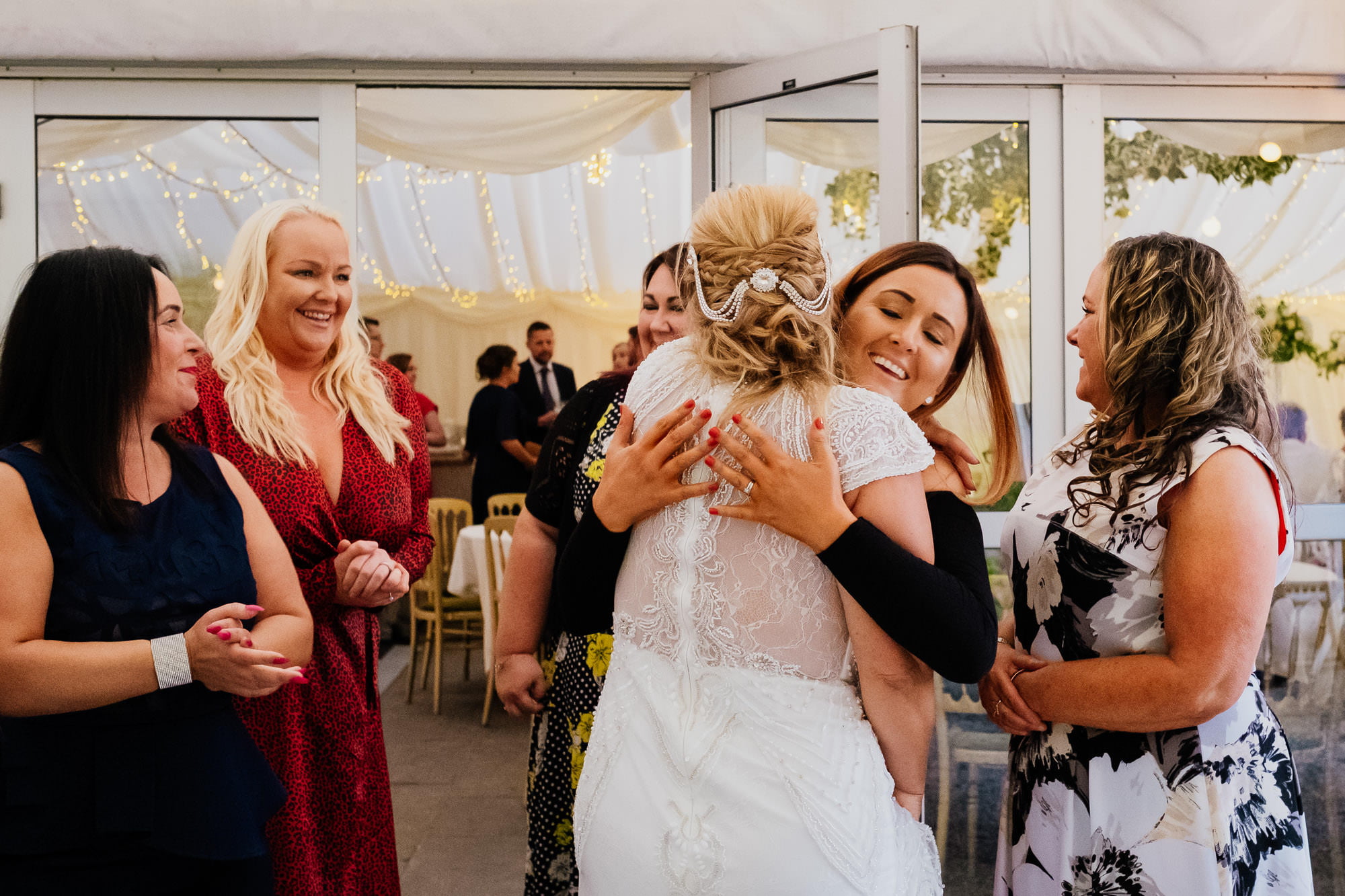 Bride hugging wedding guest outside marquee