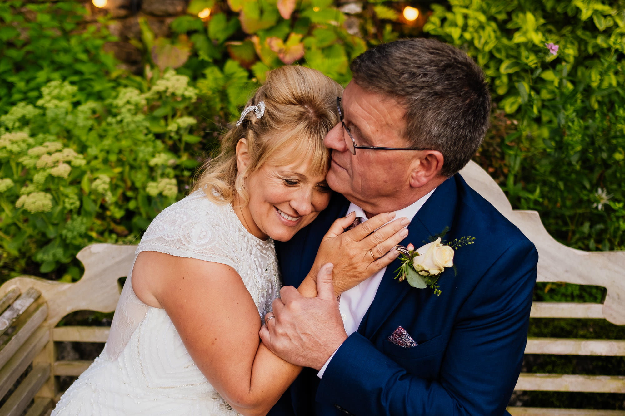 Couple snuggled closely on a bench on wedding day