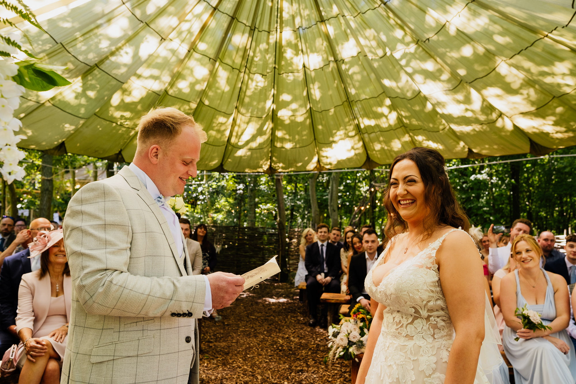 groom reading vows to bride under woodland canopy