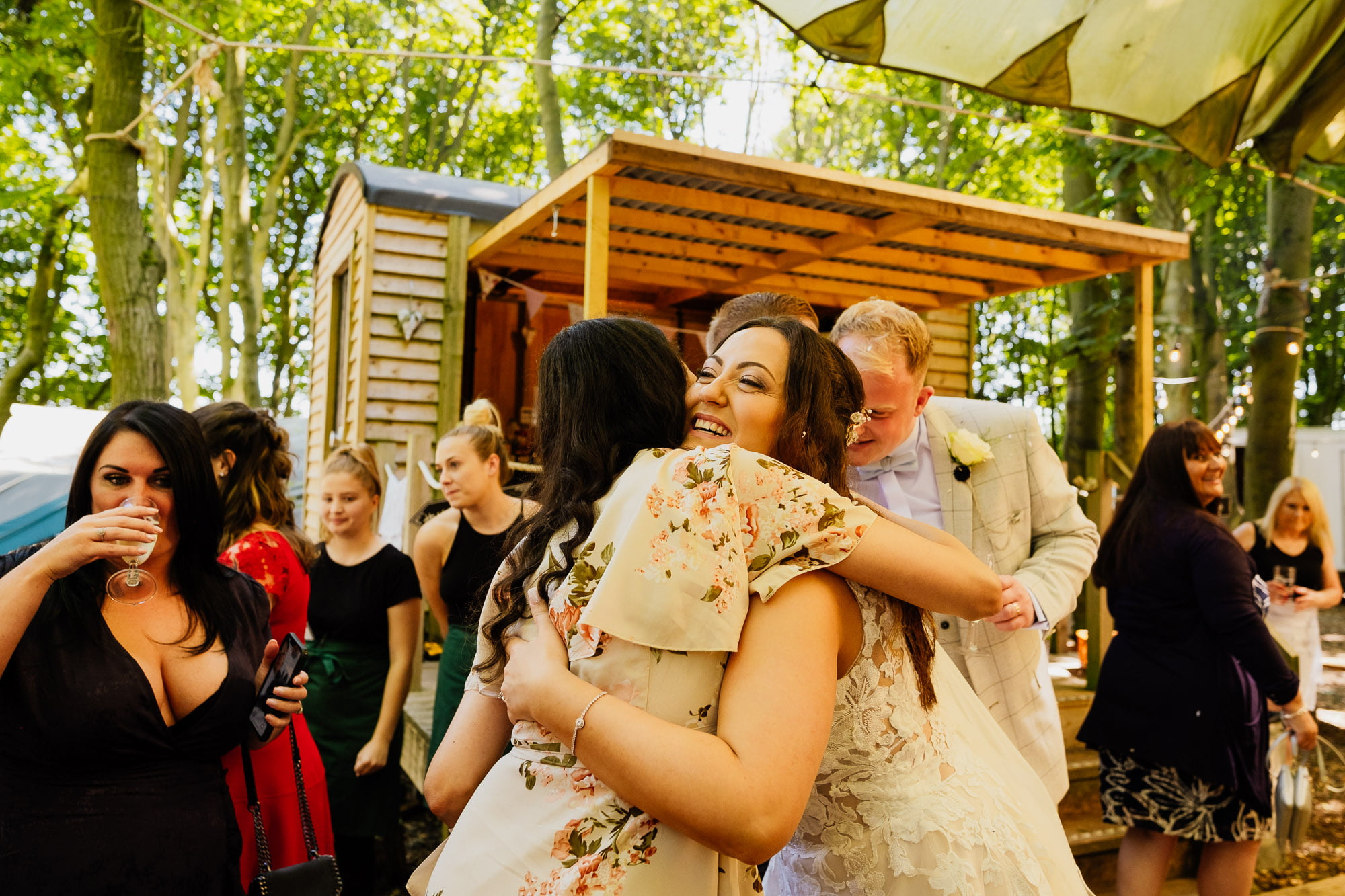 Bride hugging guest at woodland wedding reception