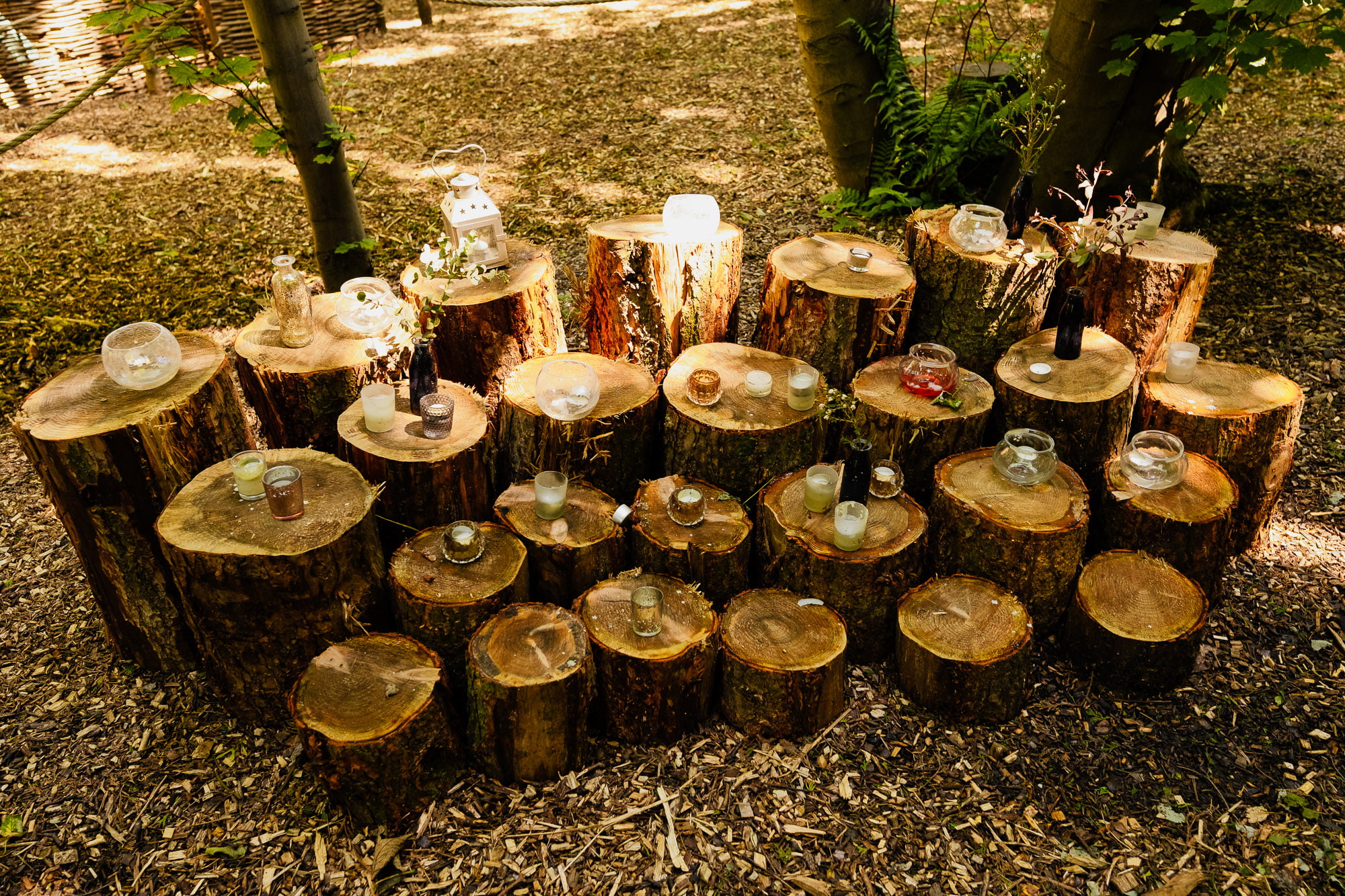 four rows of tiered tree stumps with tealights and candles on them
