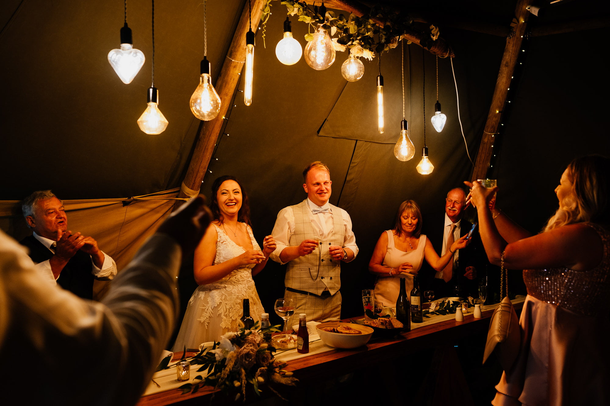 Bride and groom being cheered by wedding guests at wedding top table
