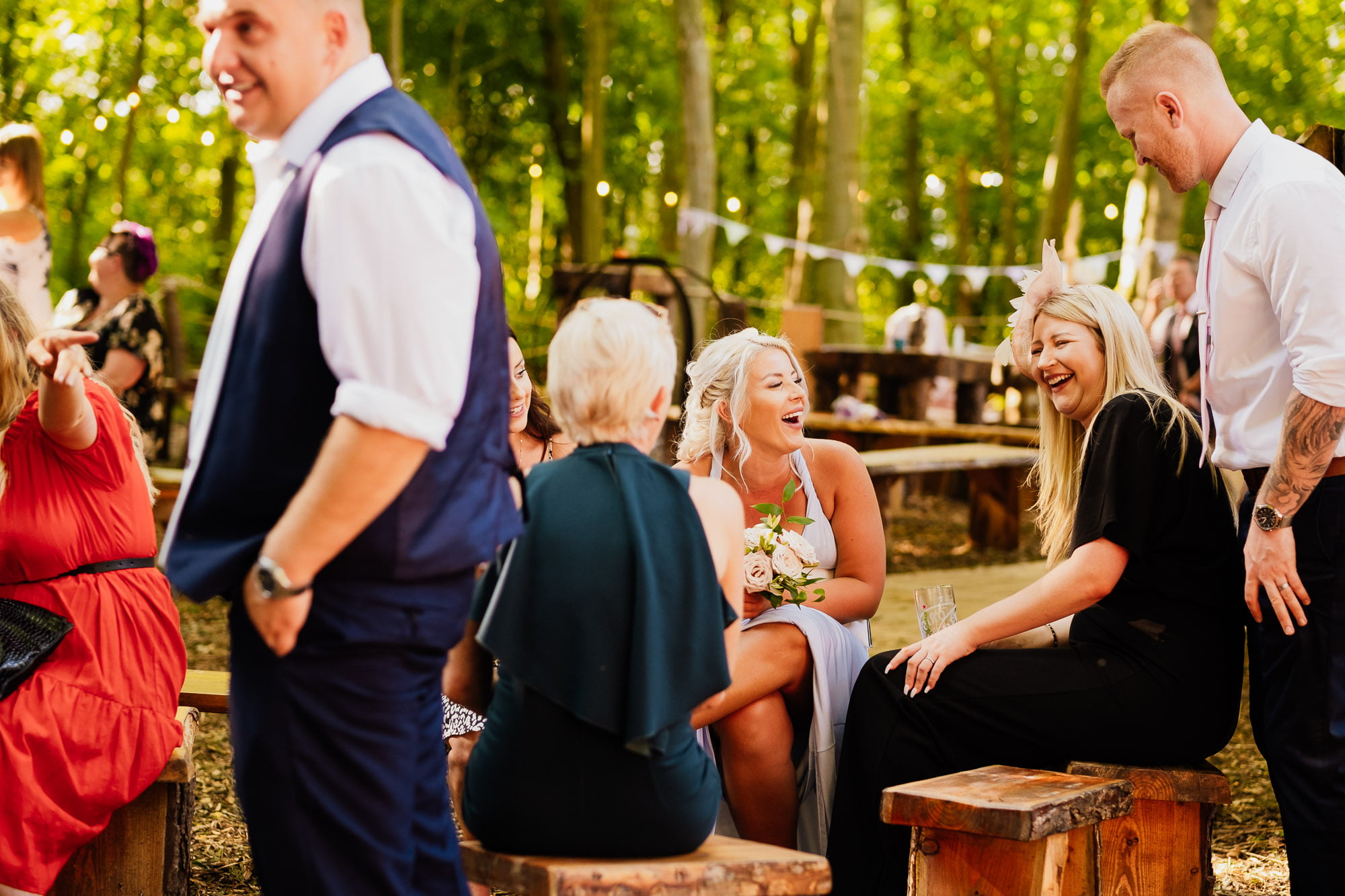 Bridesmaid sat laughing with guests at woodland wedding