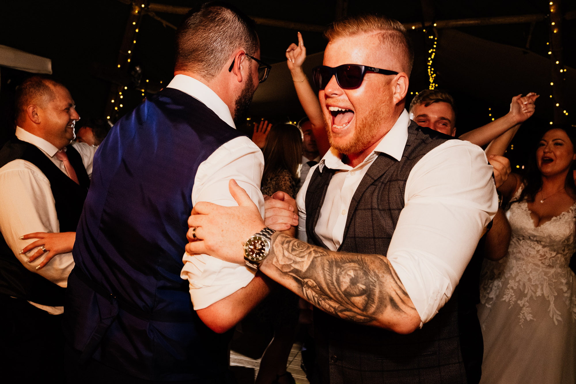 Wedding guest dancing in sunglasses in dark tipi