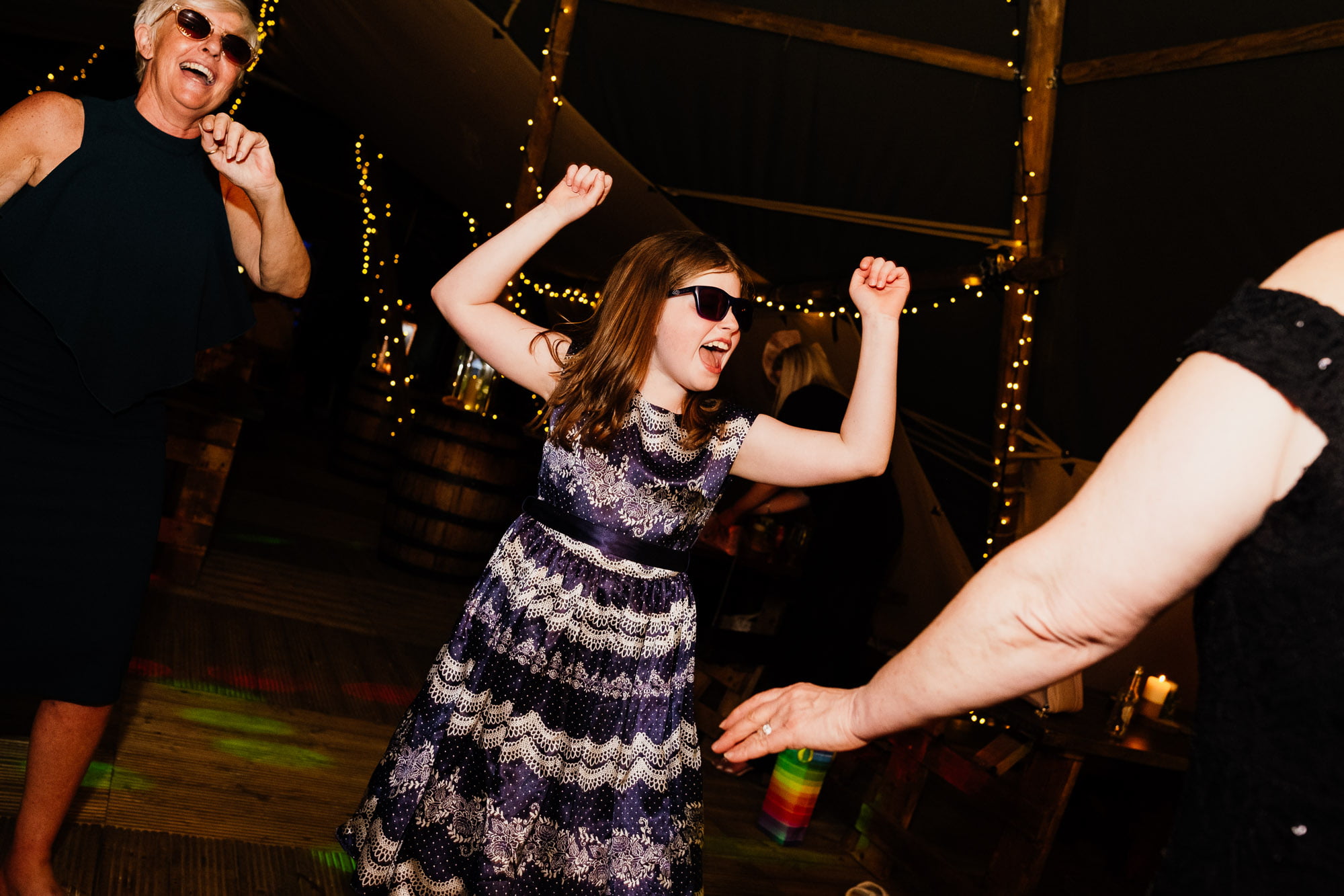 Child dancing with arms in the air and sunglasses on