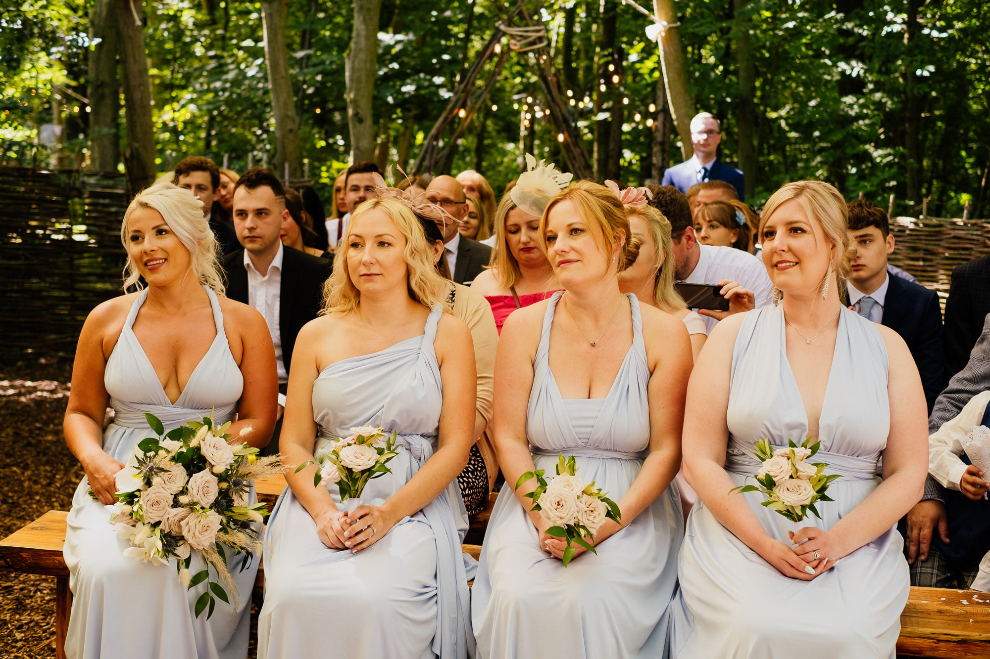 bridemaids sat during outdoor ceremony in pale blue multiway dresses