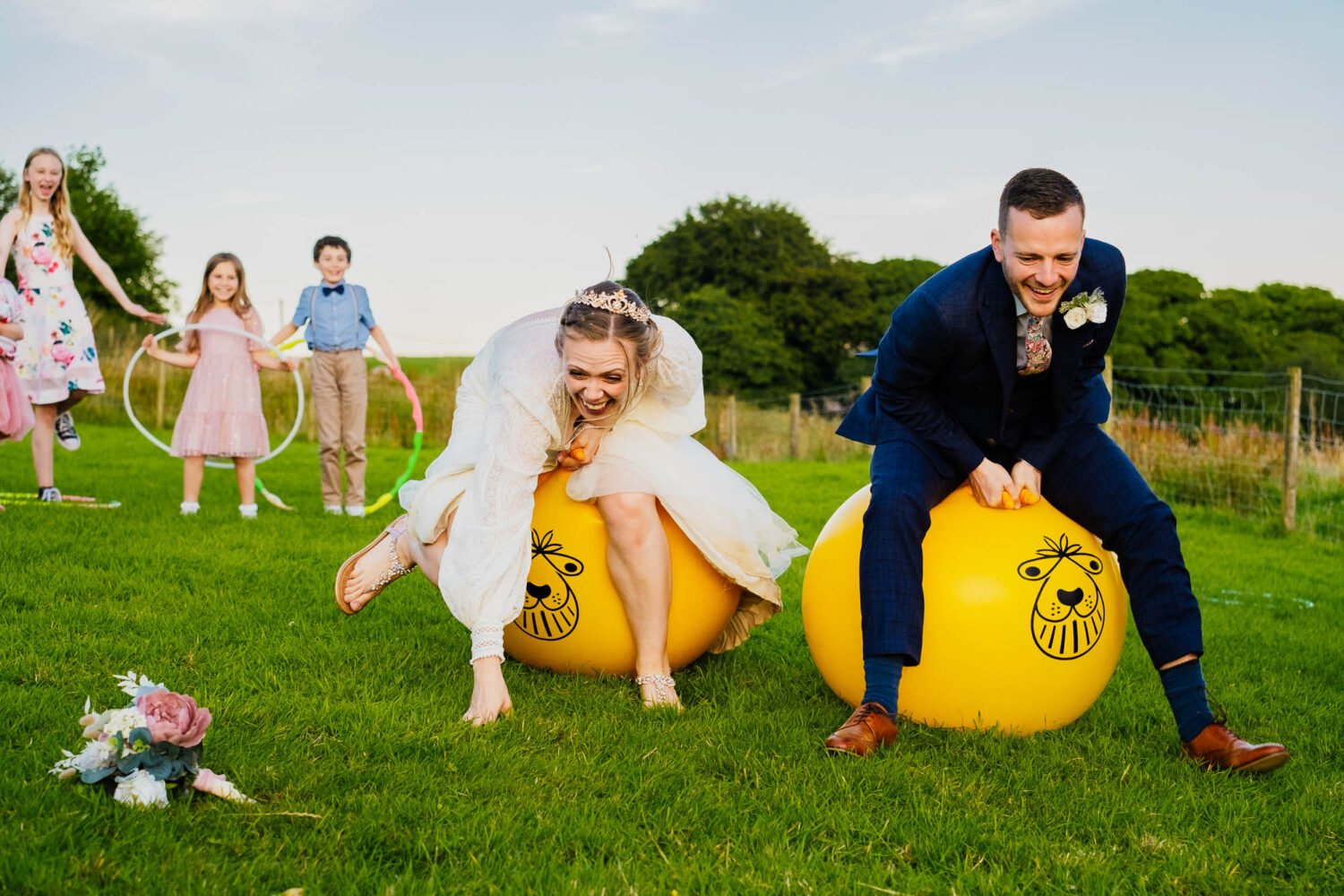 bride and groom on space hoppers at their wedding in a field
