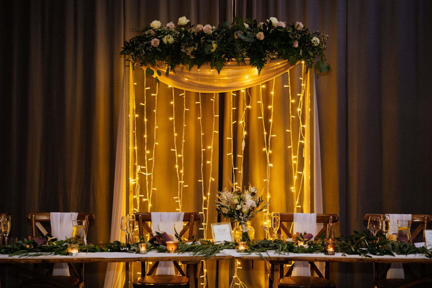Top table with fairy light curtain arbour behind