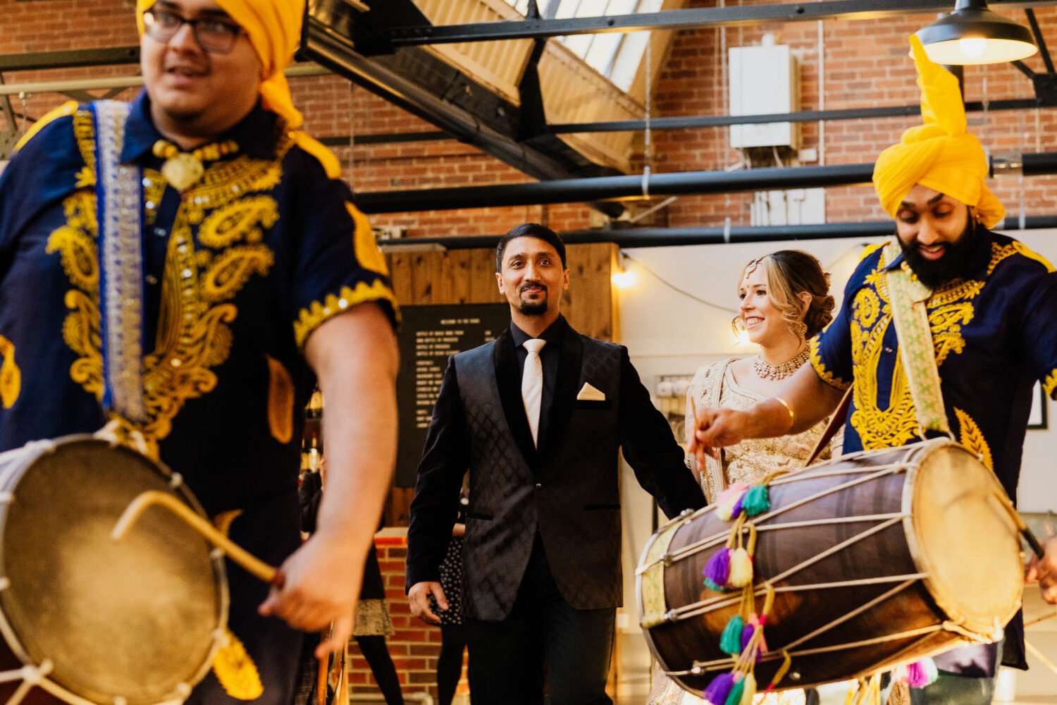 Bride and groom entrance to wedding reception with Dhol drummers in front