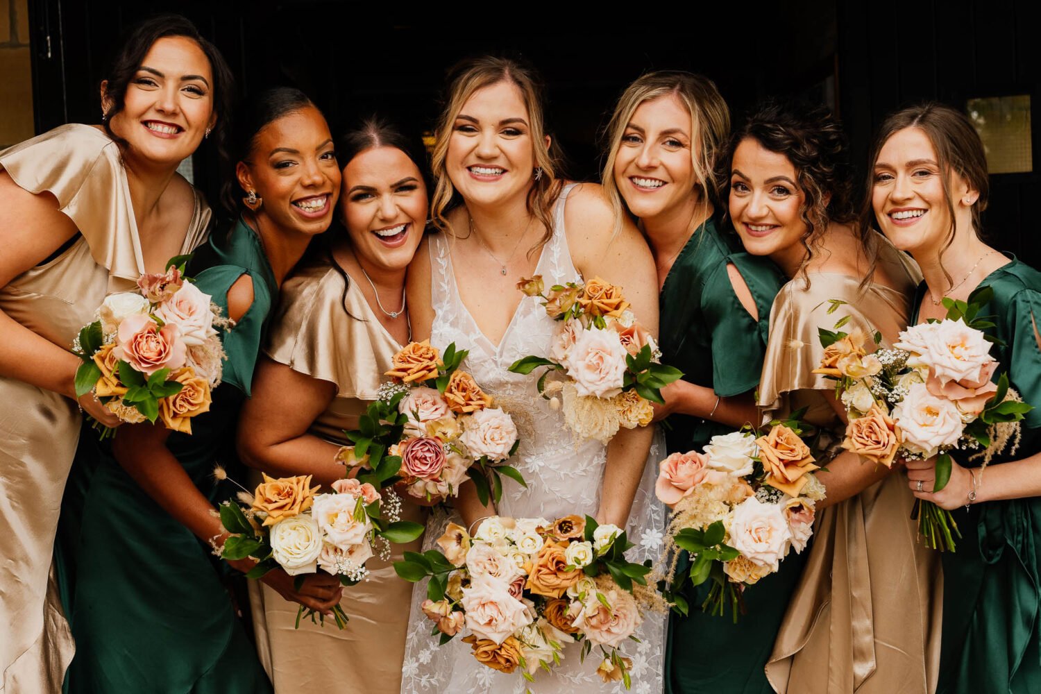 Bridal party photo with bridesmaids in champagne and dark green dresses