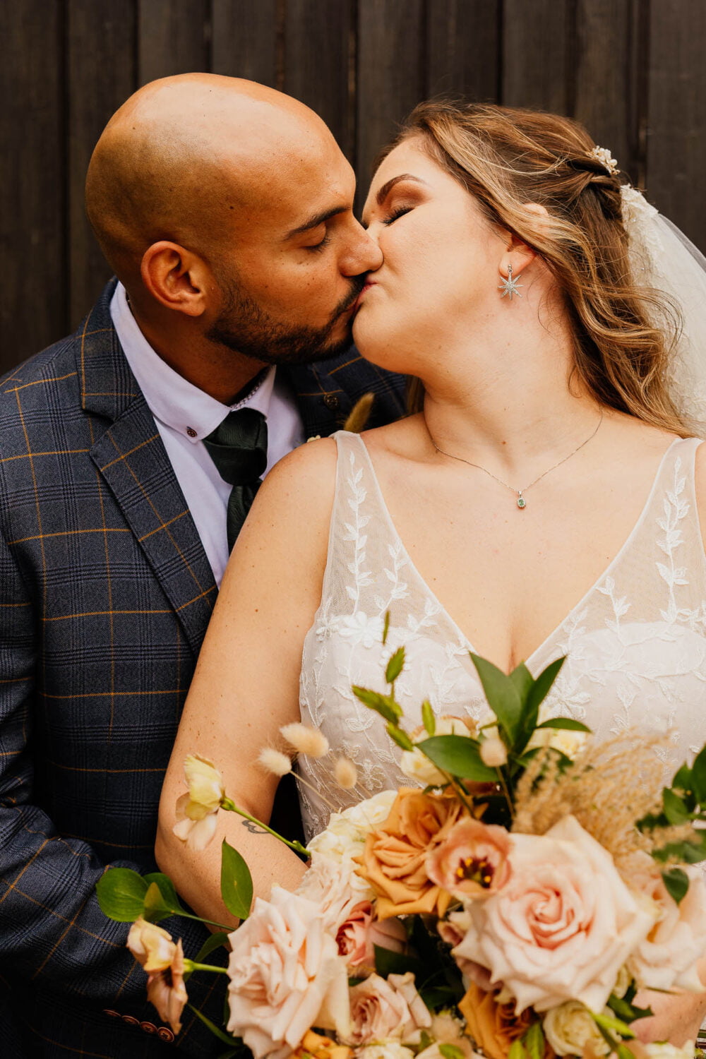 Bride and groom kiss at wedding with flowers in the foreground