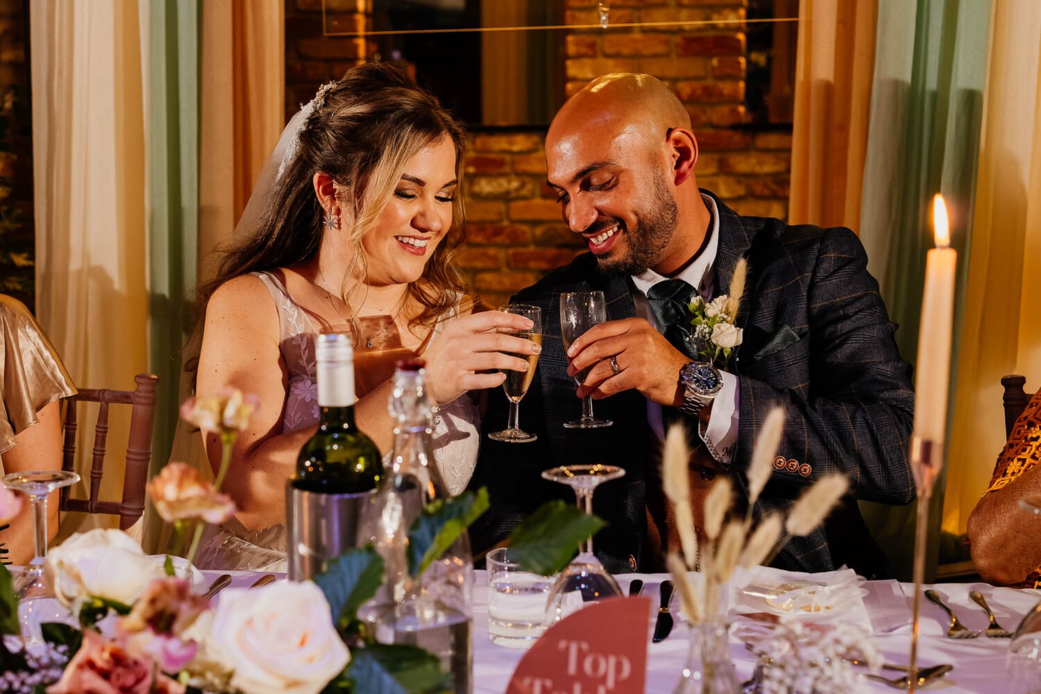 Bride and groom cheer with drinks during wedding speeches