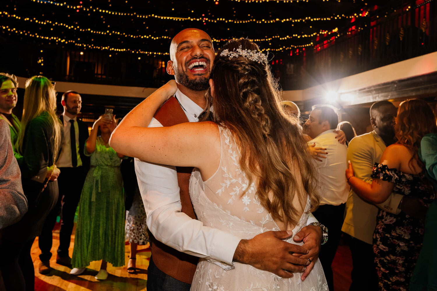 Groom hugging bride on dancefloor and laughing