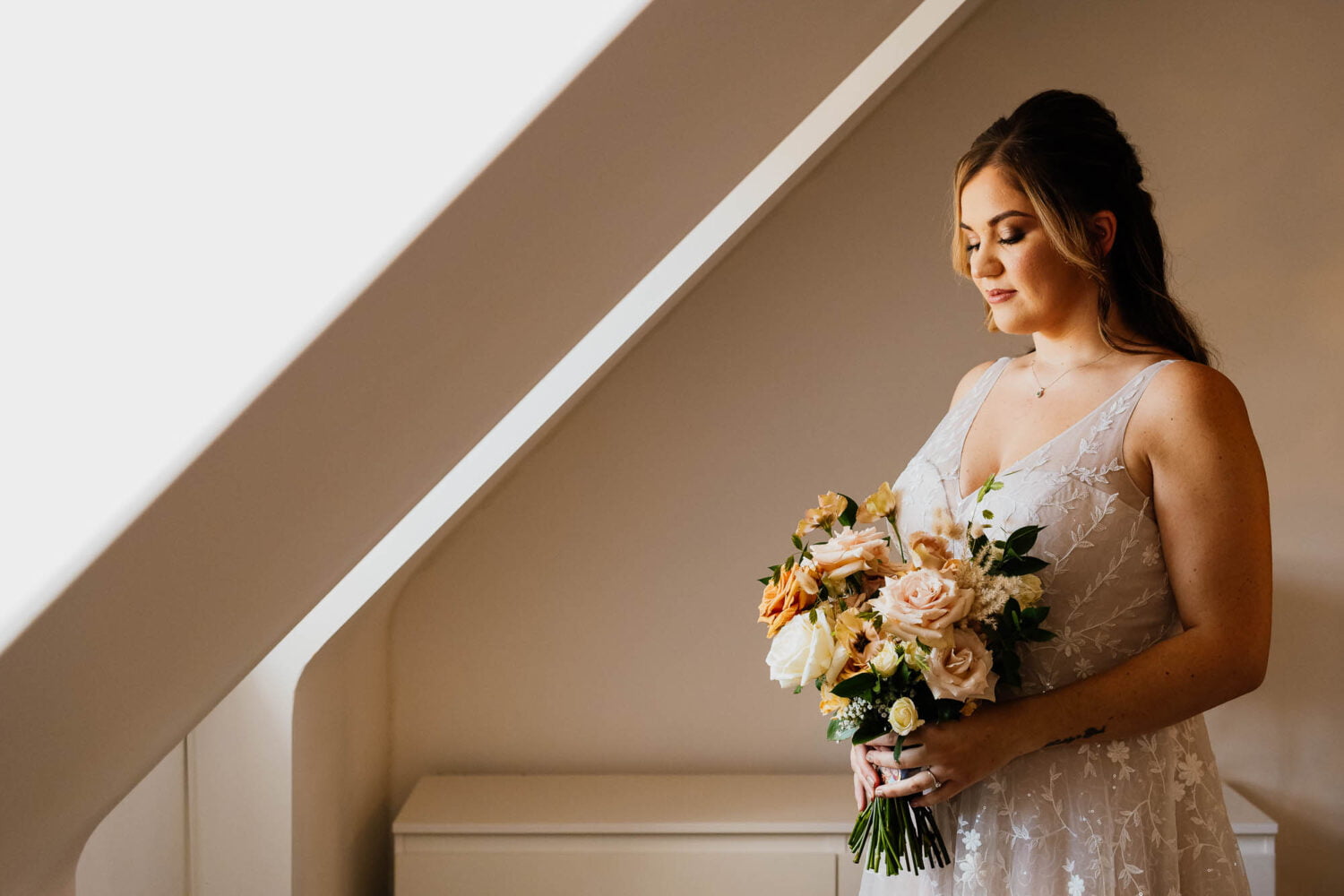 Bride portrait holding flowers next to window with sloped walls