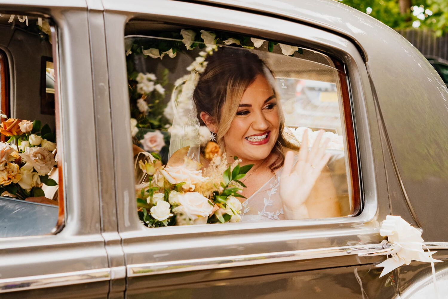 Bride arriving at The Engine Shed in car and smiling and waving