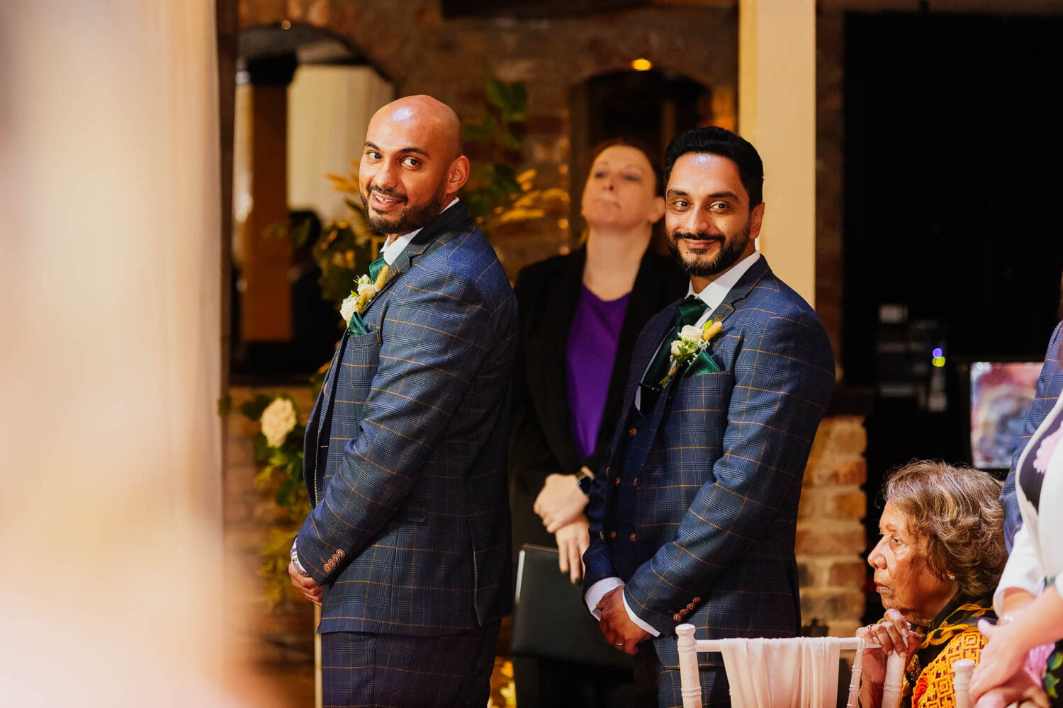 Groom and best man looking down the aisle to see the bride