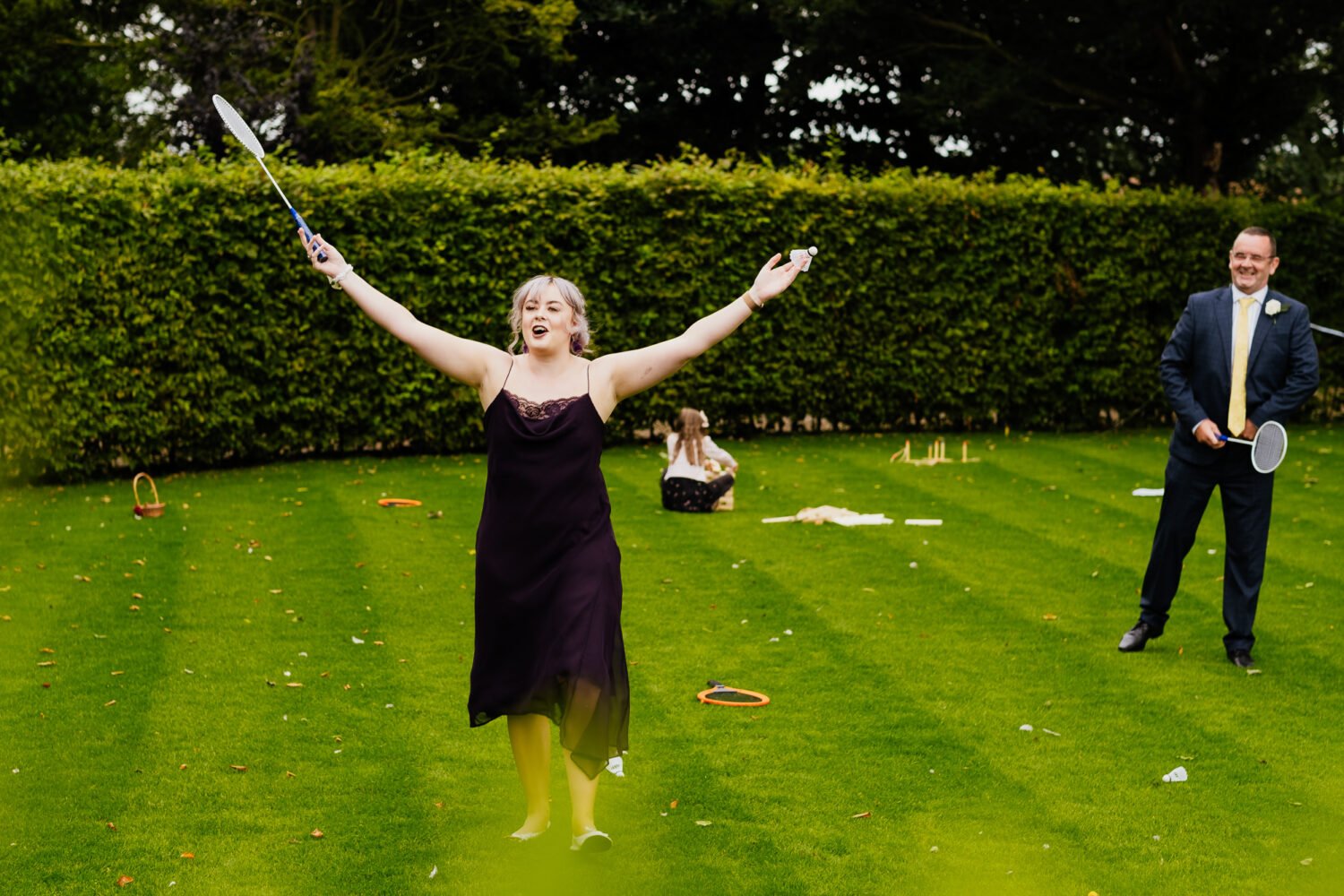 wedding guest with arms in the air celebrating badminton win