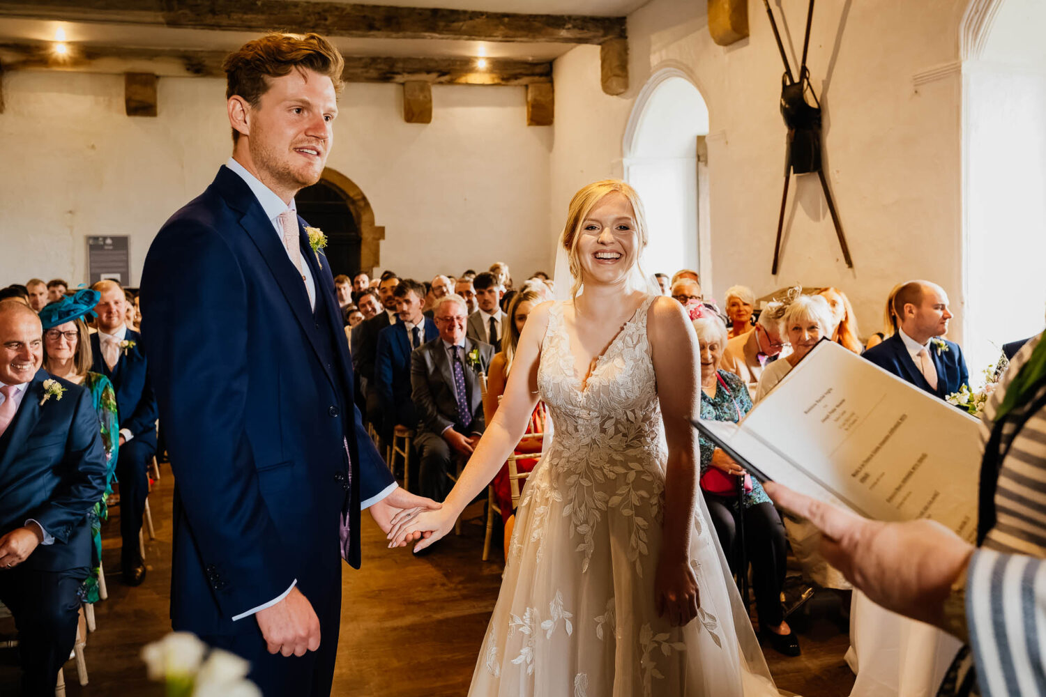Groom and bride holding hands and smiling during Bolton Castle wedding ceremony