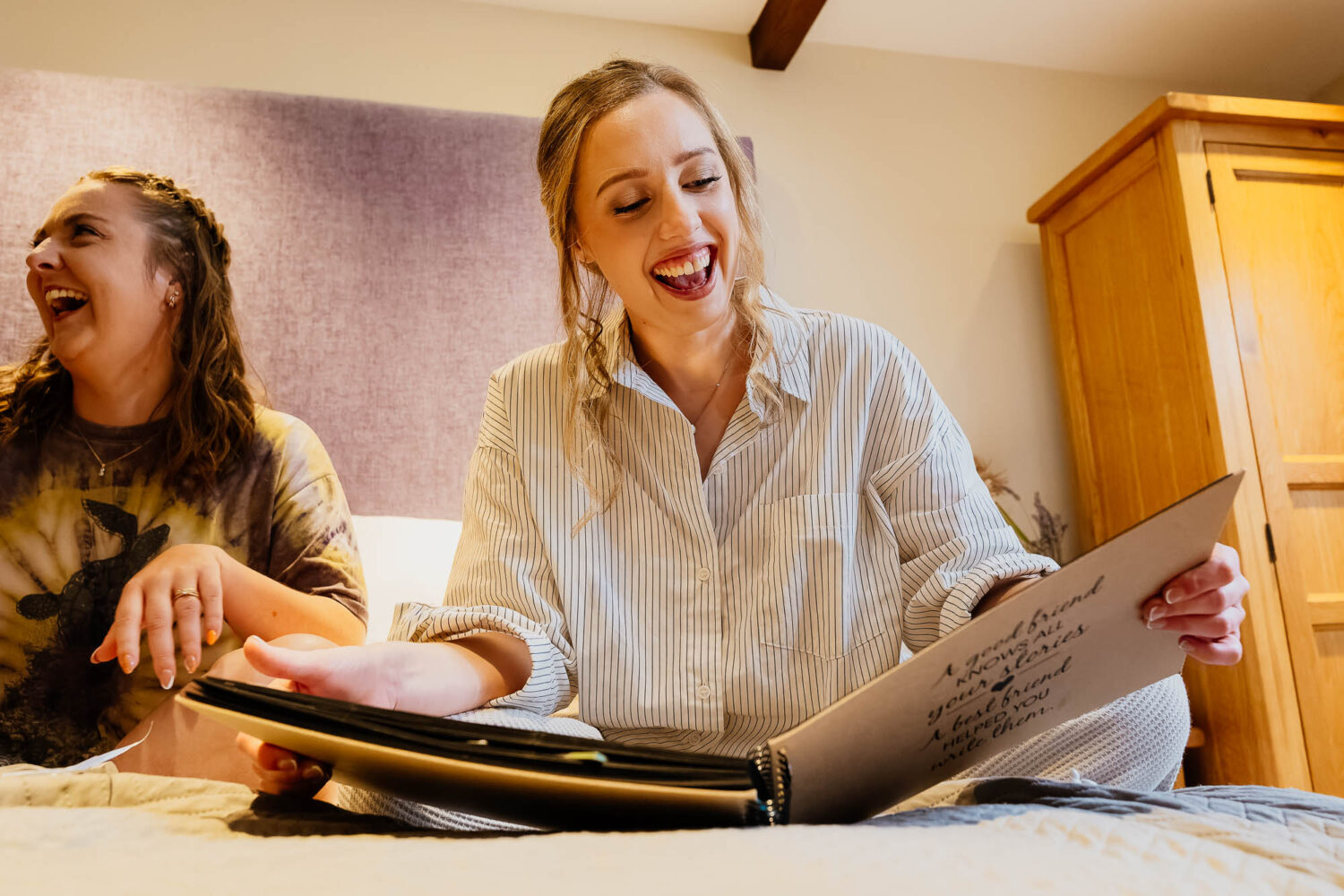 Bride reading scrapbook made by bridesmaids