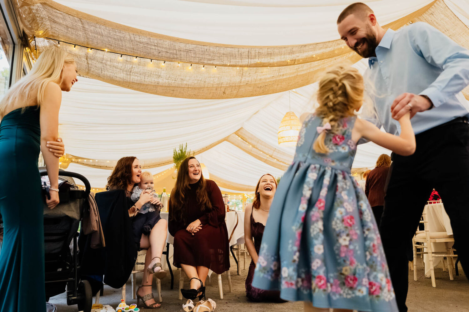 Wedding guests laughing whilst dad dances with daughter