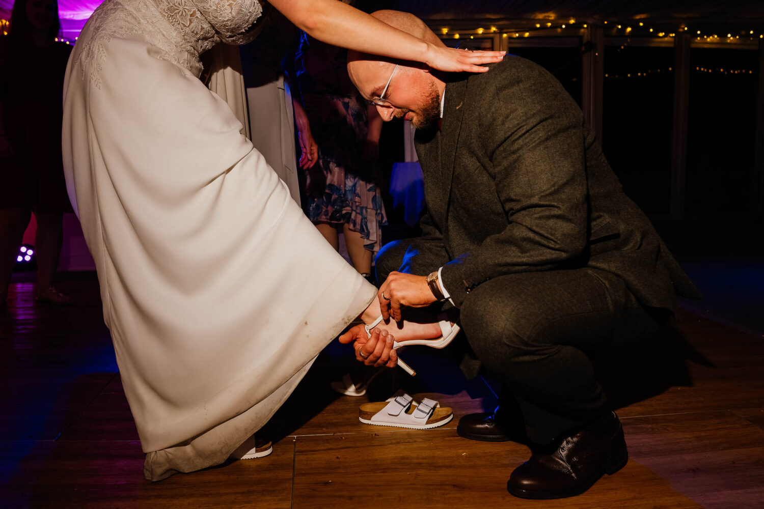 Groom changing bride's shoe on the dancefloor at The Woodman Inn