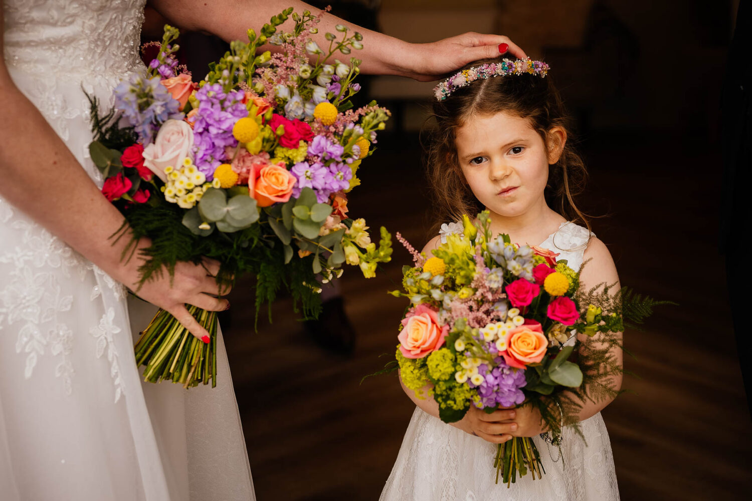 Flower girl pulling a face with mum's hand on her head