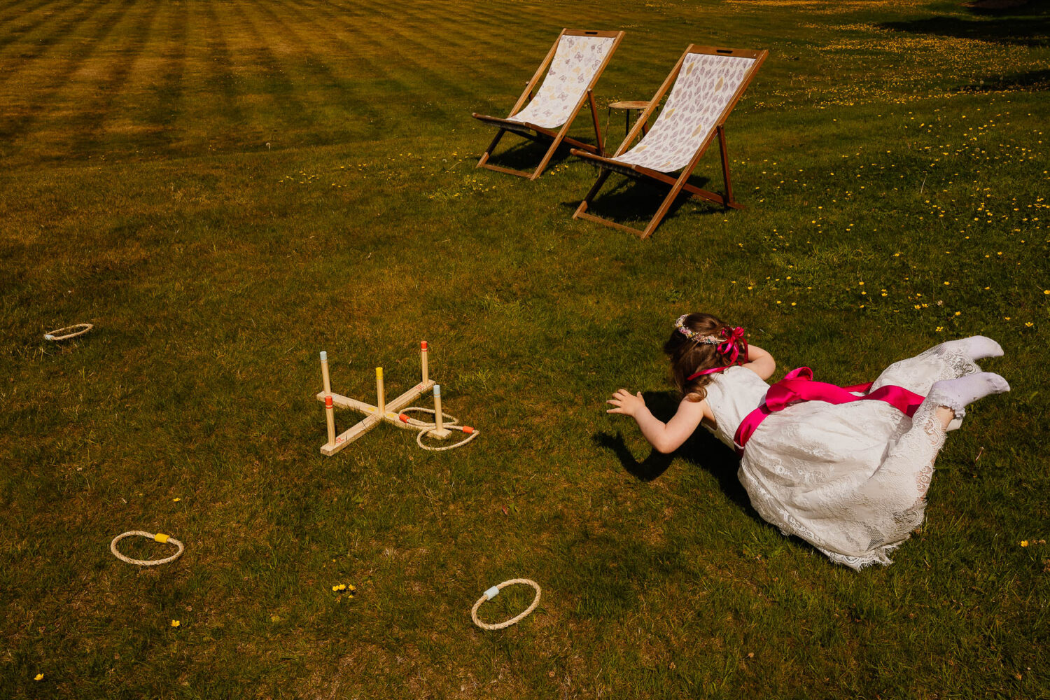 Flower girl lying on grass with deckchair and games