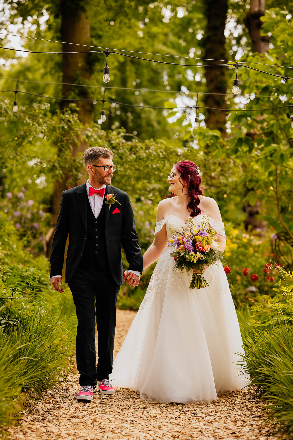 Bride and groom holding hands walking through woodland at The Love Shack