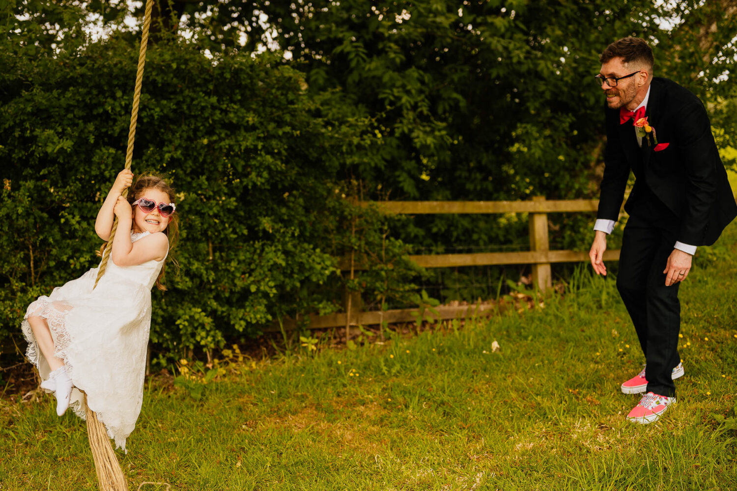 Flower girl in sunglasses on a tree swing