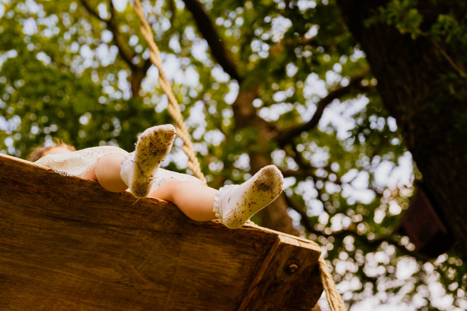 Flower girl's legs on a tree swing with dirty socks