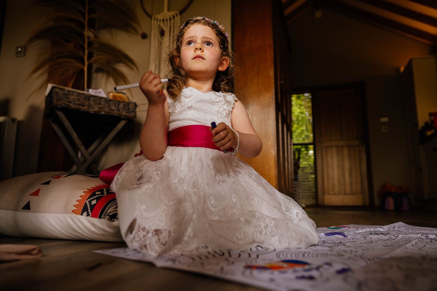 Flower girl in white dress colouring in on the floor