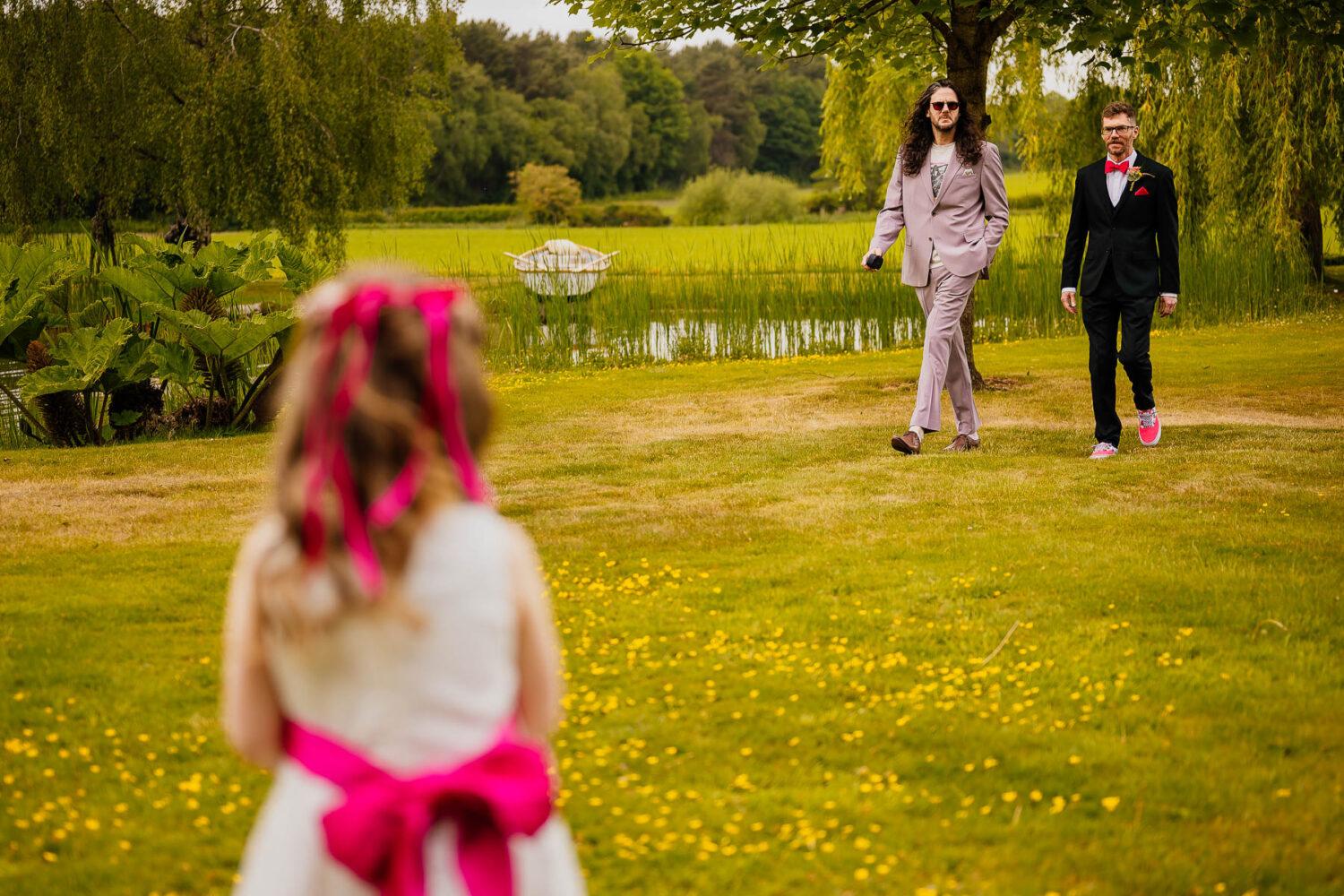 Flower girl watching as groom and best man walk towards her