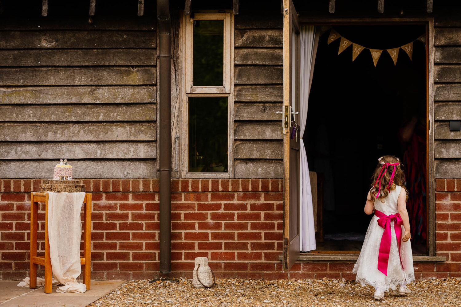 Flower girl walking into accommodation with wedding cake outside