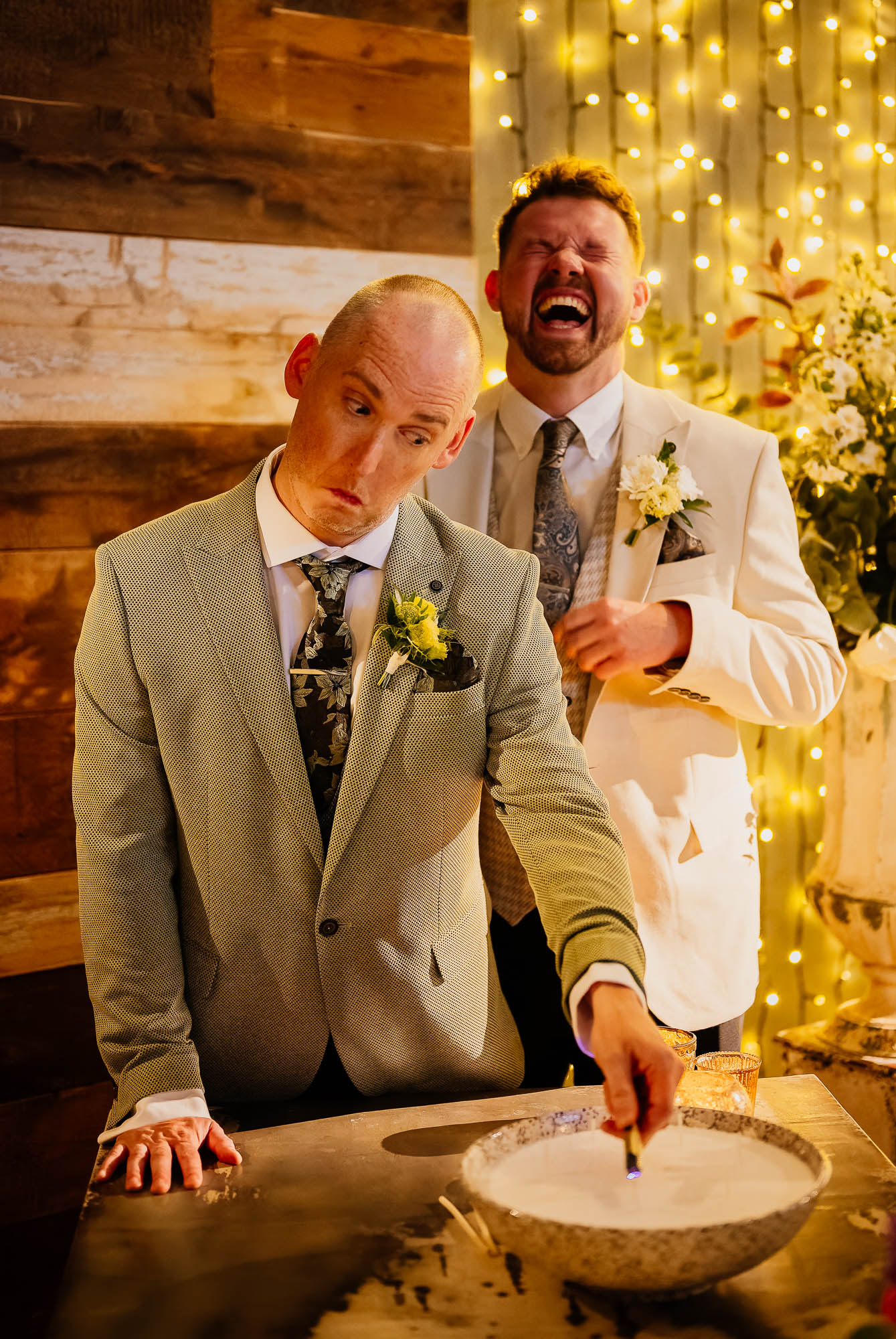 Groom lighting candle with groom laughing behind