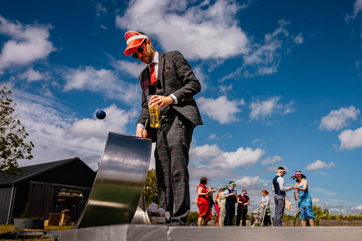 Wedding guest playing mini golf in the sun with orange hat
