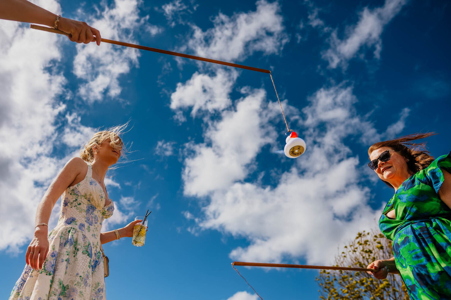 Wedding guests playing hook a duck against a blue sky