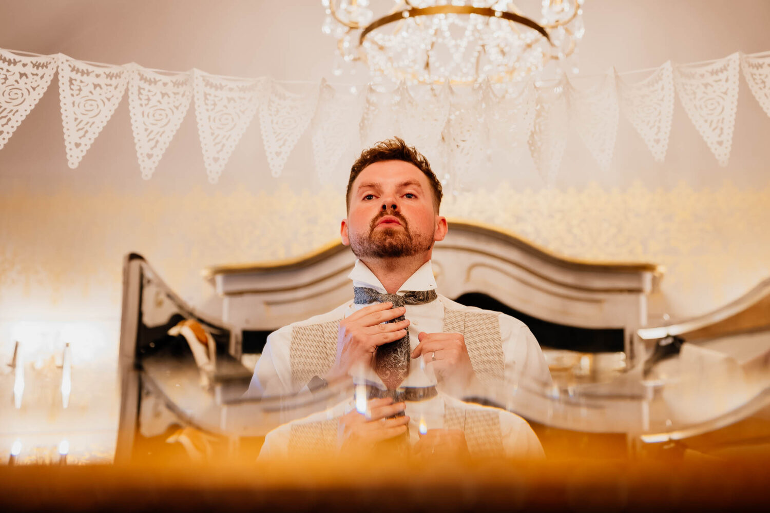 Groom fixing tie in mirror at Wharfedale Grange