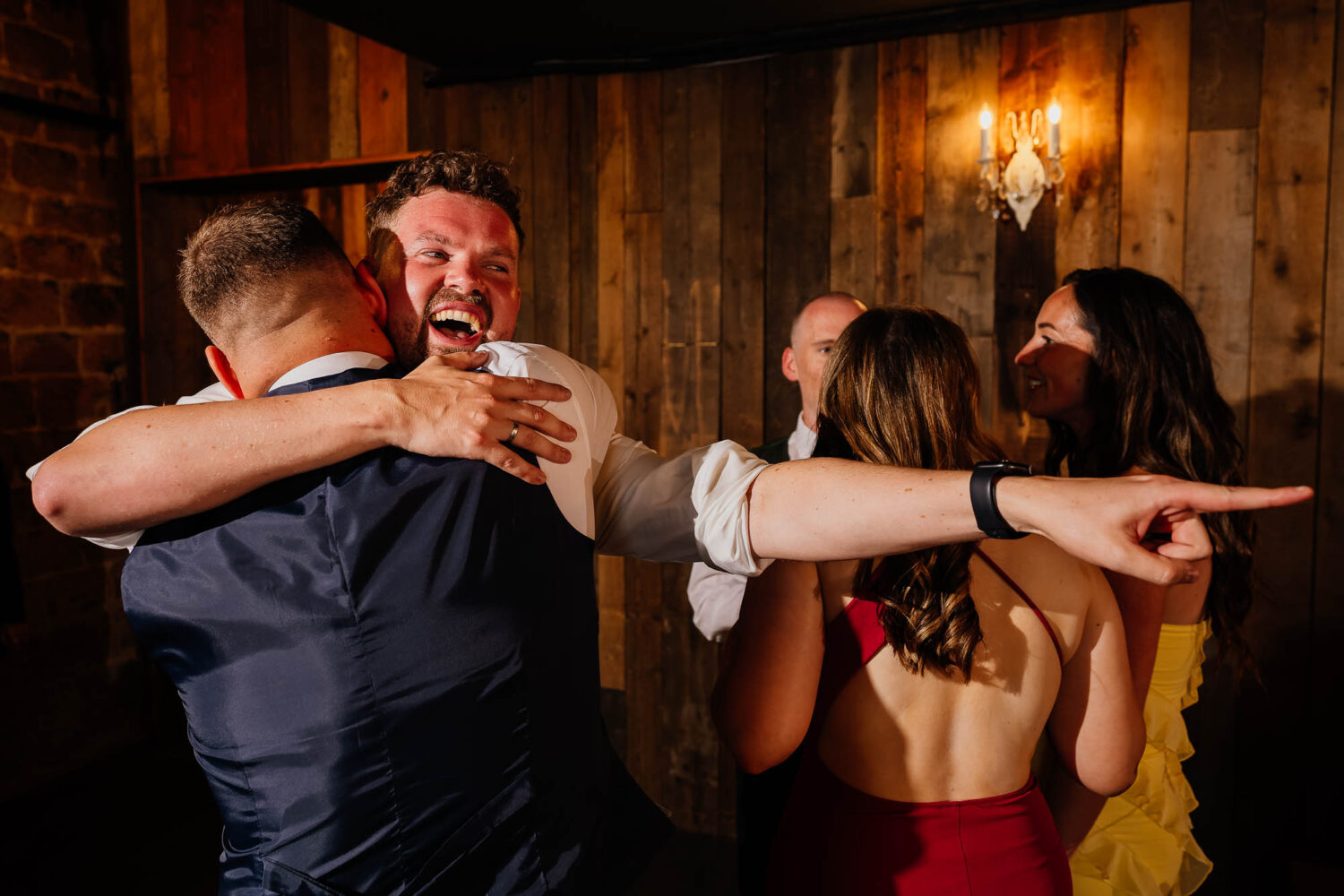 Groom hugging friend and pointing