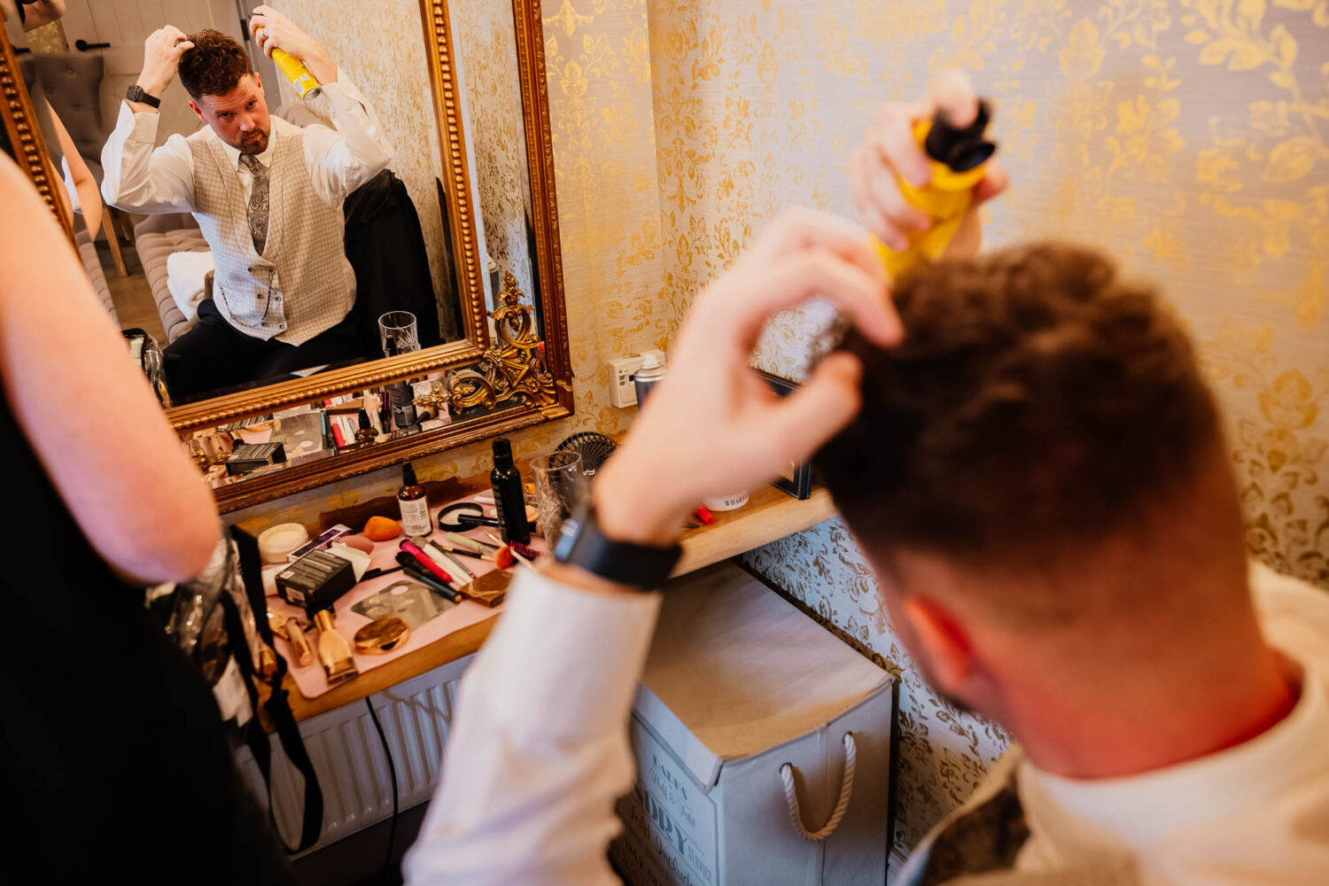 Reflection of groom spraying hairspray