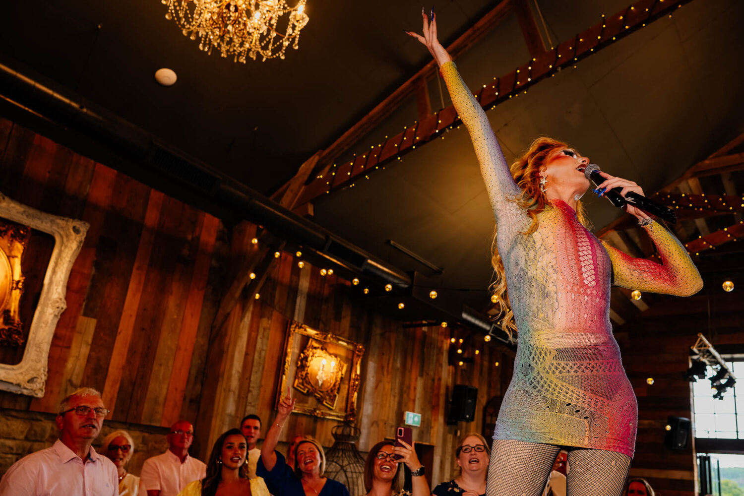 Drag queen singing with guests watching