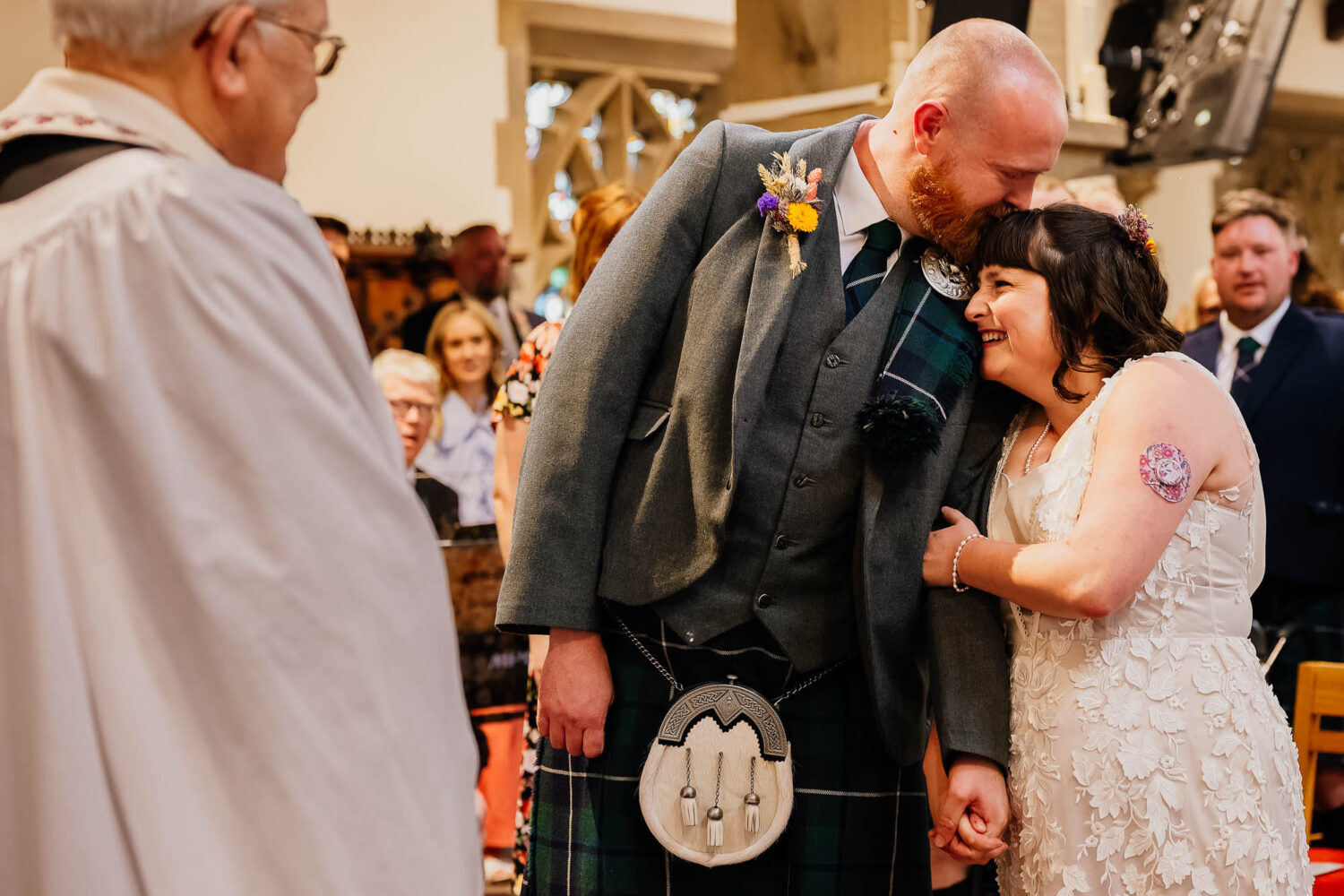 Bride cuddling up to groom during church wedding ceremony