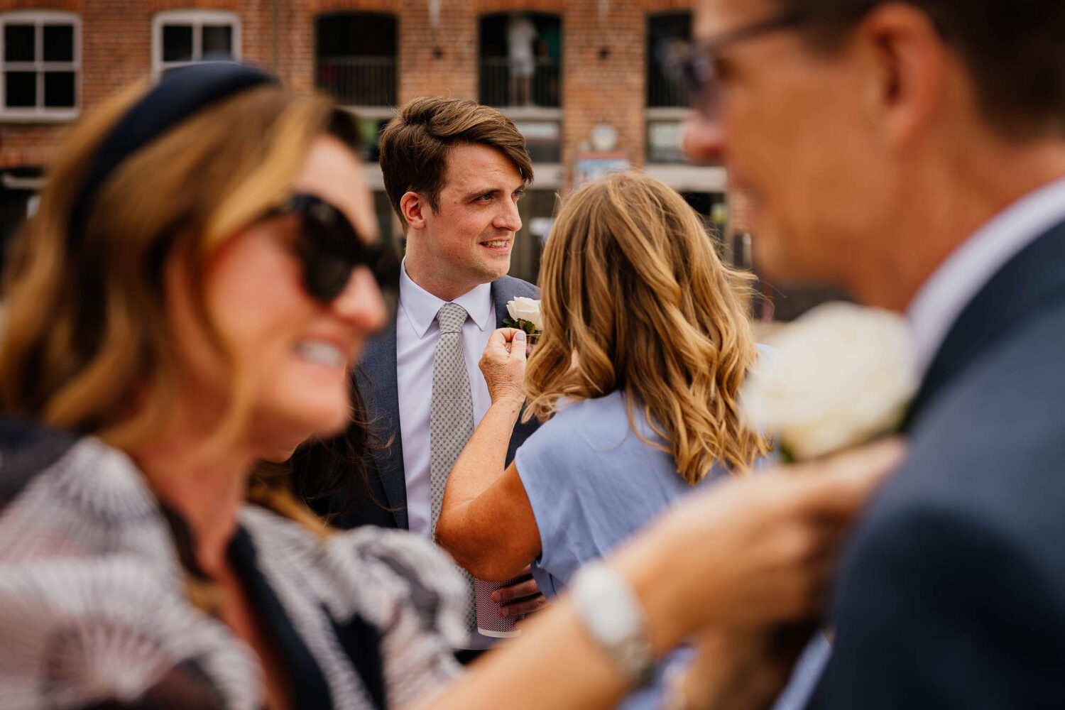 Groom having button hole pinned on with dad having his pinned on in the foreground