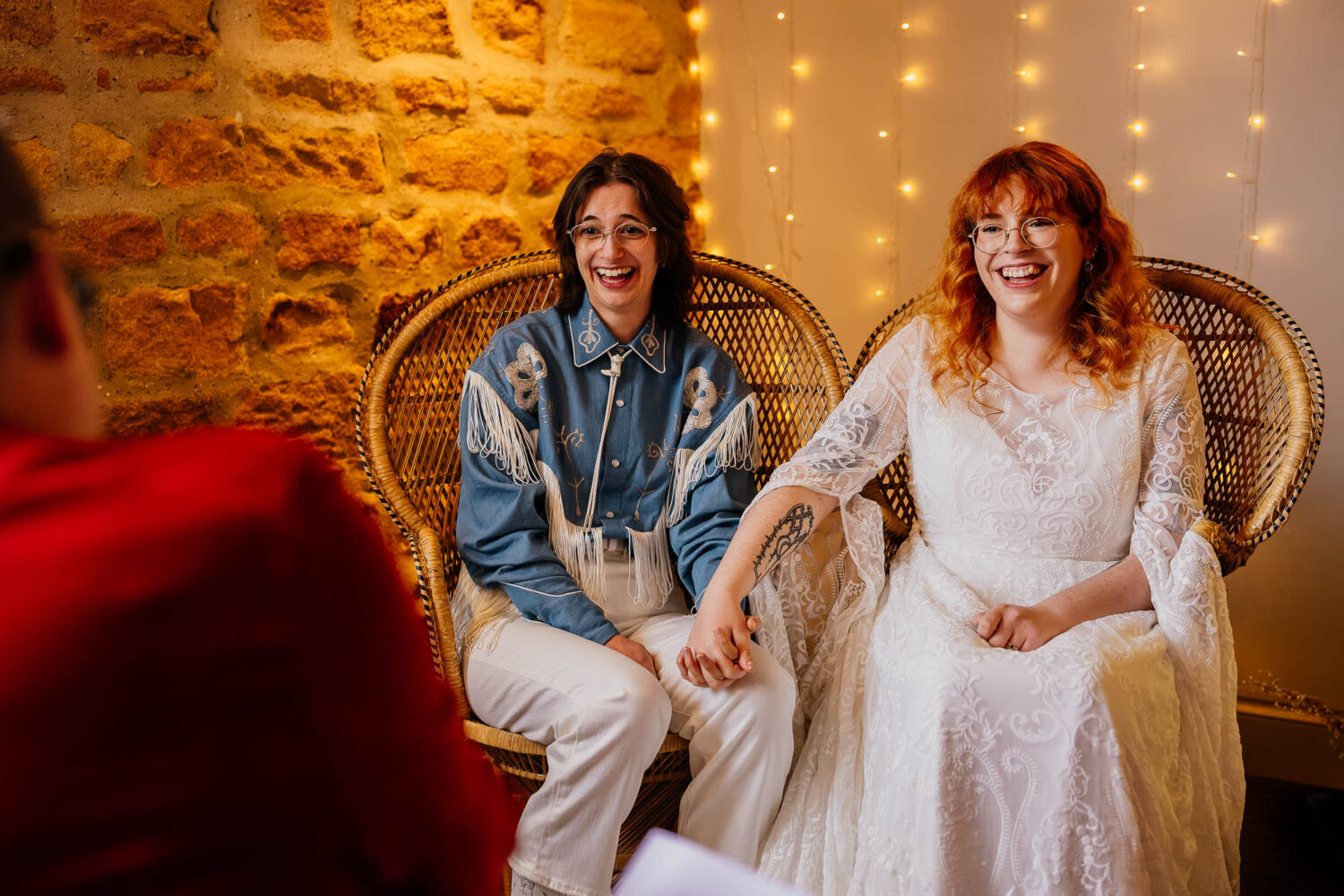 Couple laughing on peacock chairs during ceremony