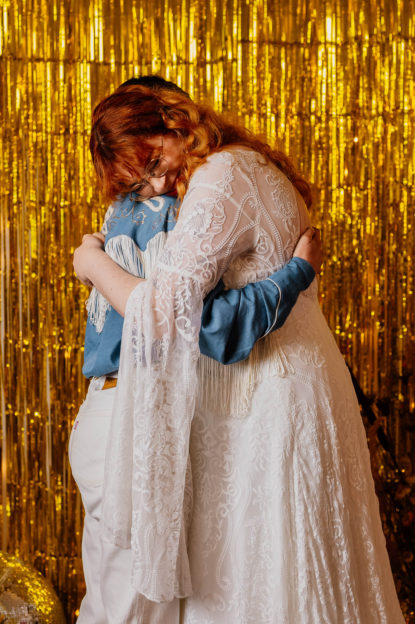 Couple hugging in front of gold foil backdrop
