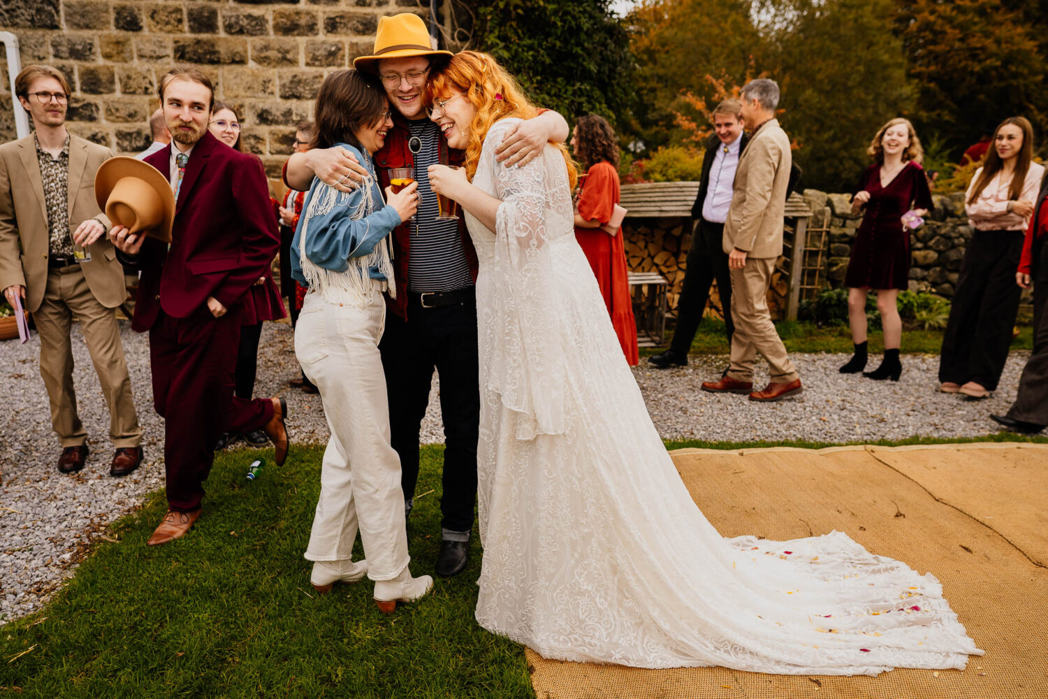 Couple being hugged by friend after wedding