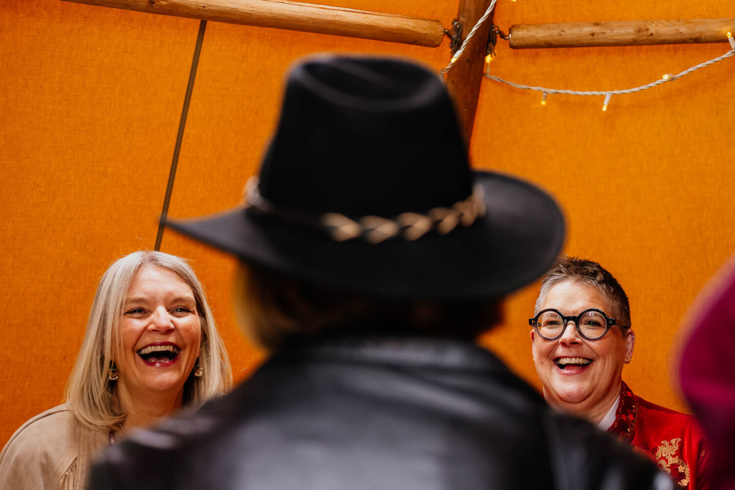 Two women laughing between a woman in a large cowboy hat