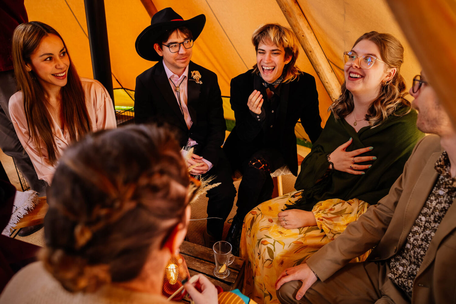 Group of friends laughing in a wedding tipi