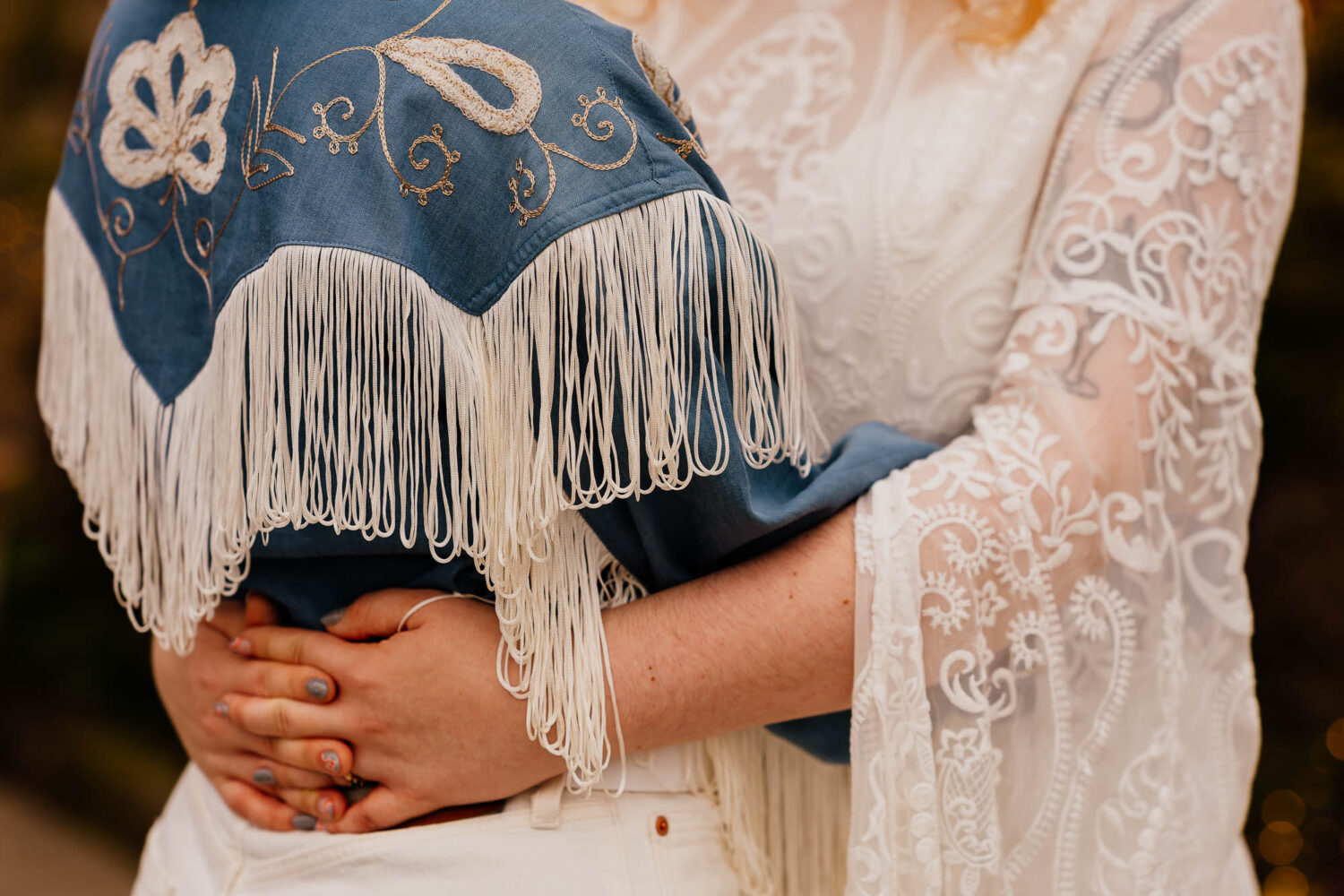 Close up of fringe cowboy shirt with couple hugging