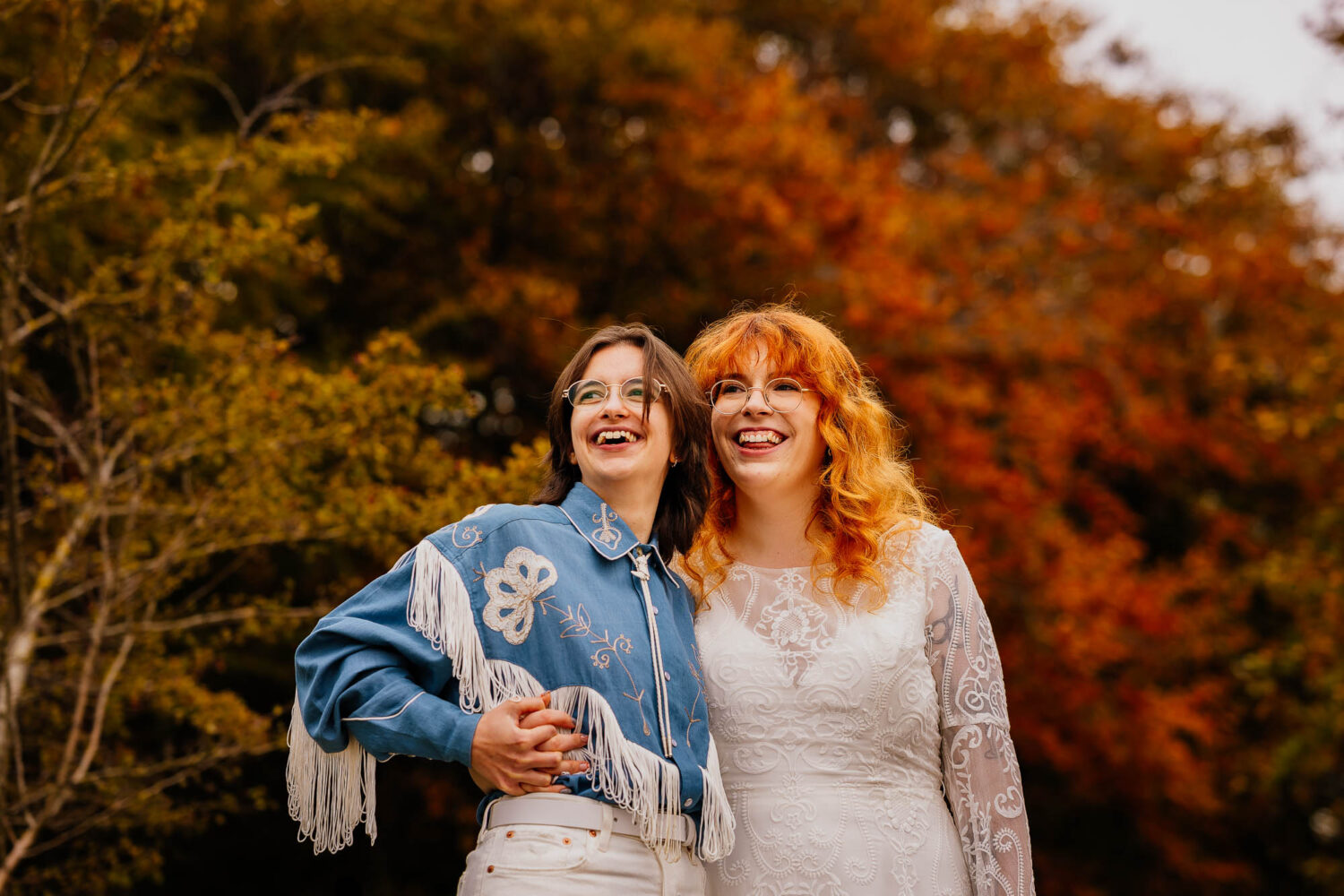 Couple laughing with autumn trees in the background