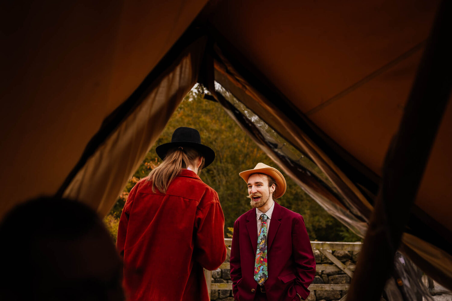 Two men in cowboy hats framed by tipi entrance